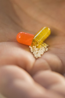 Close up of open medication capsule in man’s hand.