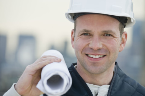 Male construction worker holding blueprints.
