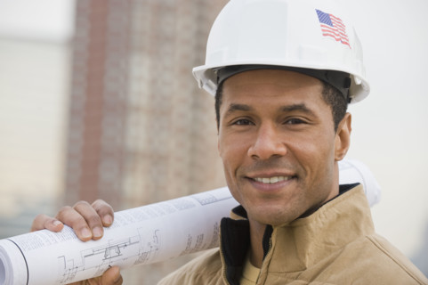 African male construction worker holding blueprints.