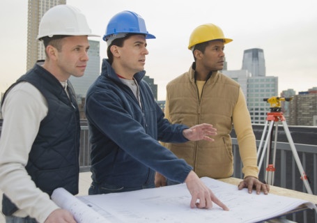 Multi-ethnic construction workers with blueprints.