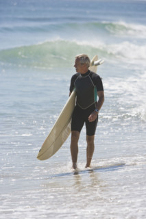 Man carrying surfboard at beach.
