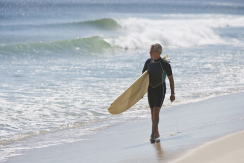 Man carrying surfboard at beach.