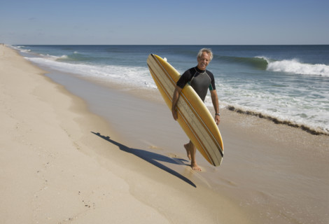 Man carrying surfboard at beach.