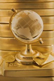 Globe in front of stack of gold bars.