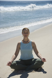 Woman practicing yoga at beach.
