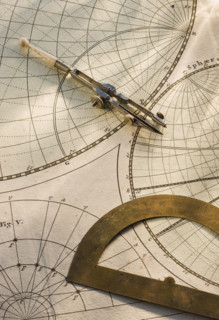 Protractor and drafting compass on antique map.