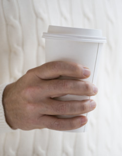 Close up of man holding take out coffee.