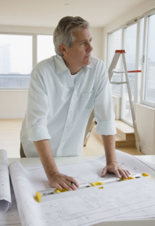 Man with level and blueprints.