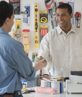 African sales clerk at hardware store handing over credit card.