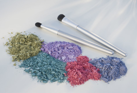 Assorted crushed cosmetics next to brushes.