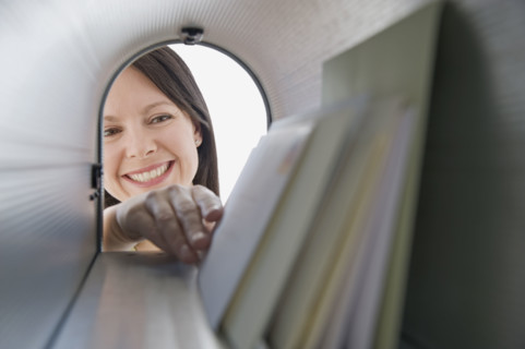 Woman reaching into mailbox for mail.