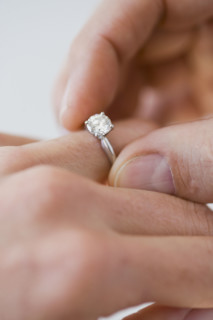 Man putting engagement ring on woman’s finger.