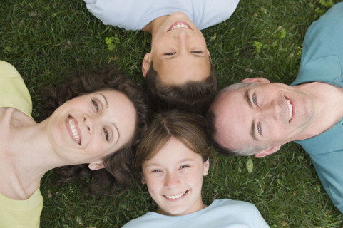 Family with two children laying on grass.