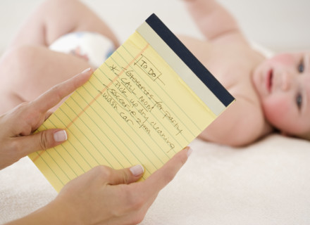 Mother looking at To Do list in front of baby. Date : 2008