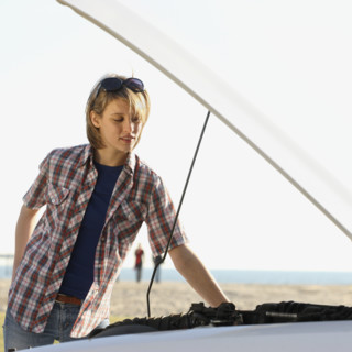 Woman looking under car hood. Date : 2008