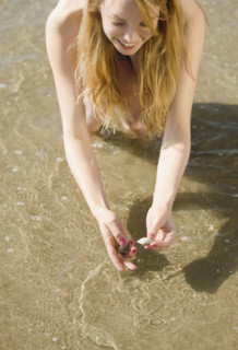 Woman picking up seashells at beach. Date : 2008