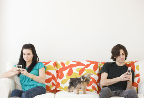 Man and woman dialing cell phones on opposite ends of sofa. Date : 2008