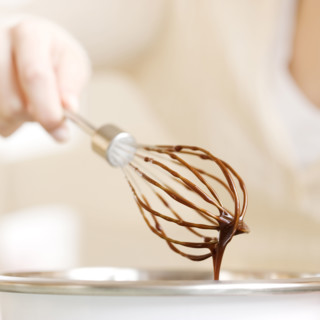 Woman holding whisk with chocolate batter. Date : 2008