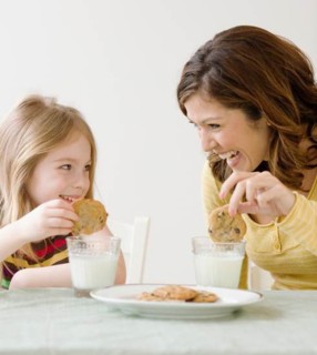 Mother and daughter dunking cookies in milk. Date : 2008