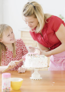 Mother and daughter decorating birthday cake. Date : 2008