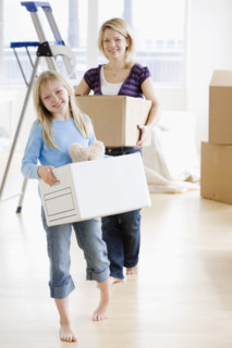 Mother and daughter carrying moving boxes. Date : 2008