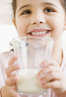 Hispanic girl holding glass of milk. Date : 2008