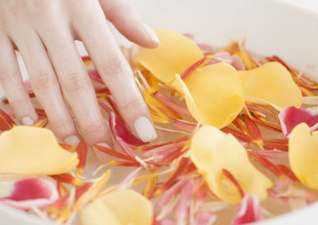 Woman with hand in bowl of water and flower petals. Date : 2008