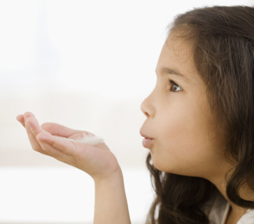 Hispanic girl blowing on feather in hand. Date : 2008