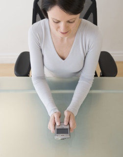 Businesswoman looking at electronic organizer.