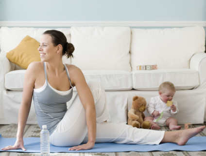 Mother practicing yoga next to baby on floor. Date : 2008