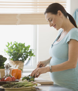 Pregnant Hispanic woman chopping vegetables.