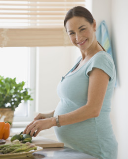 Pregnant Hispanic woman chopping vegetables.