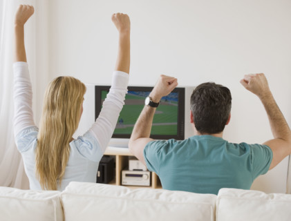 Couple cheering at television .