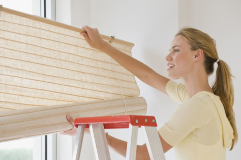 Woman hanging window blinds.