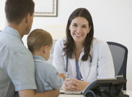 Female doctor talking to father and son.