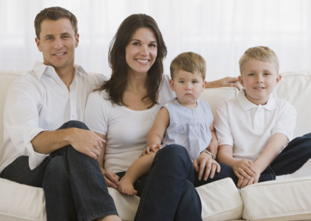 Family with two children sitting on sofa.