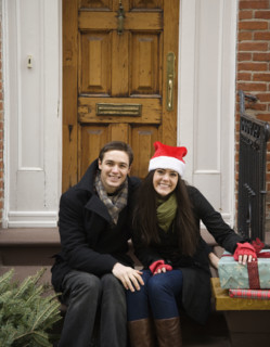 Couple with Christmas tree and gifts in front of door. Date : 2008