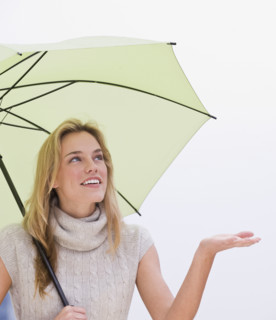 Woman holding hand out from under umbrella.
