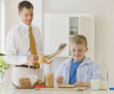 Father watching son make sandwich.