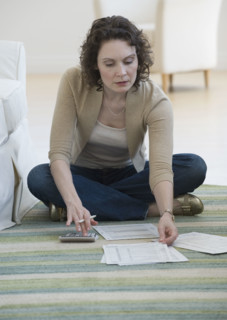 Woman paying bills on floor.