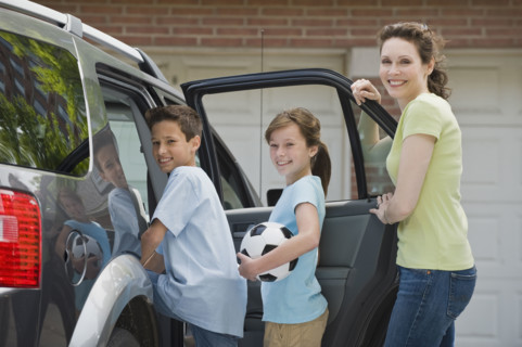 Mother and children getting into car with soccer ball.