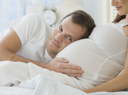Hispanic man resting head on pregnant wife.