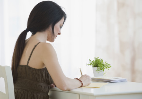 Woman writing at desk.