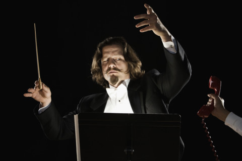 Telephone being handed to orchestral conductor. Date : 2008