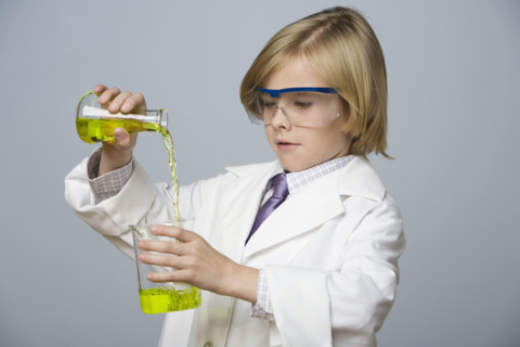 Boy pouring liquid into beaker. Date : 2008