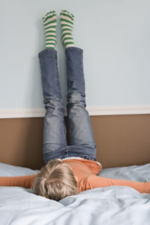 Girl laying on bed with feet on wall. Date : 2008