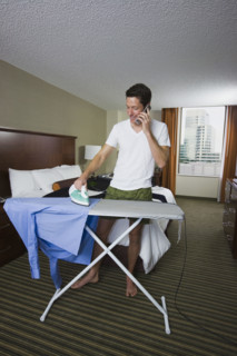 Businessman ironing shirt and talking on cell phone. Date : 2008