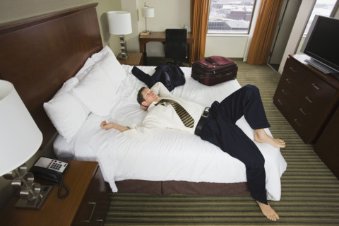 Businessman laying on hotel bed. Date : 2008