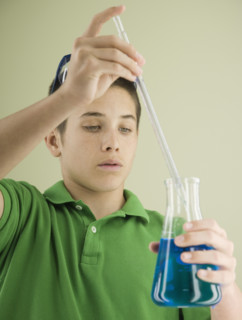 Boy measuring liquid in beaker. Date : 2008