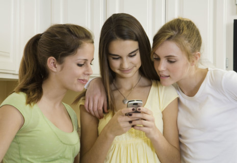 Teenaged girls looking at cell phone. Date : 2008